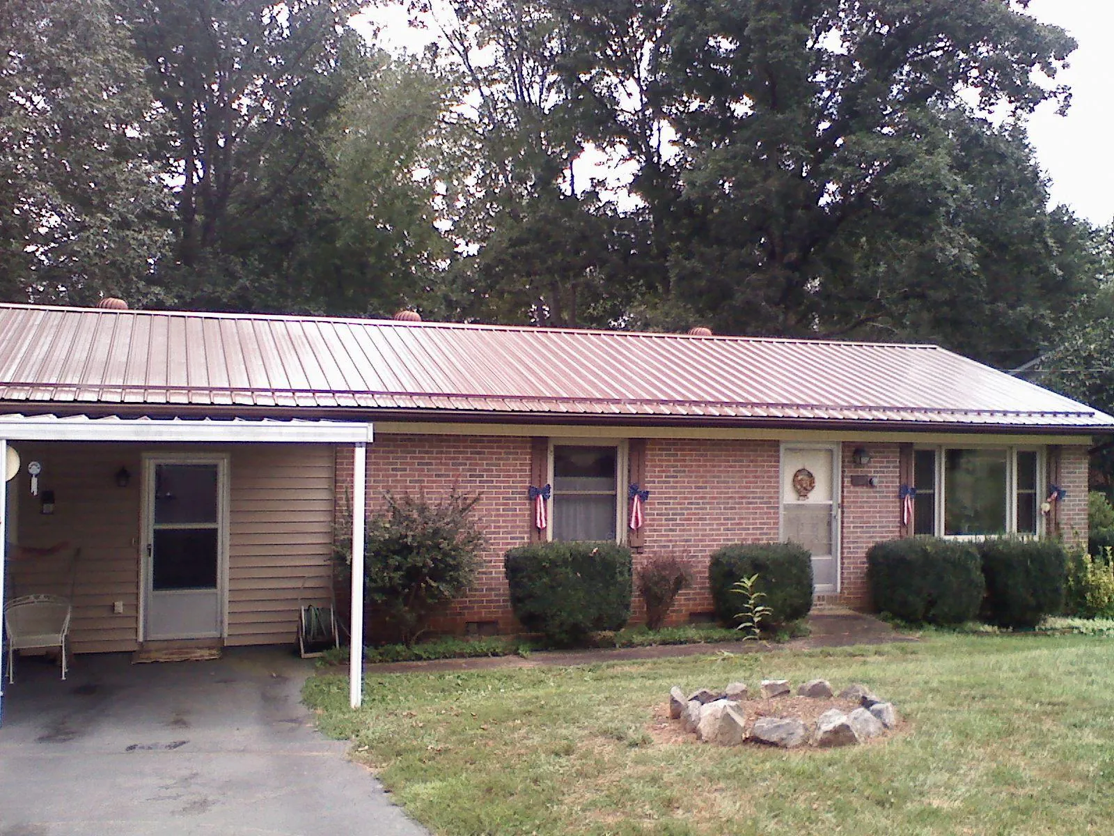 Bronze metal roof and carport on a brick ranch home — Roof Repair work by our crew in Bonanza